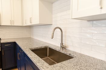 A kitchen with a sink and a white tile backsplash.